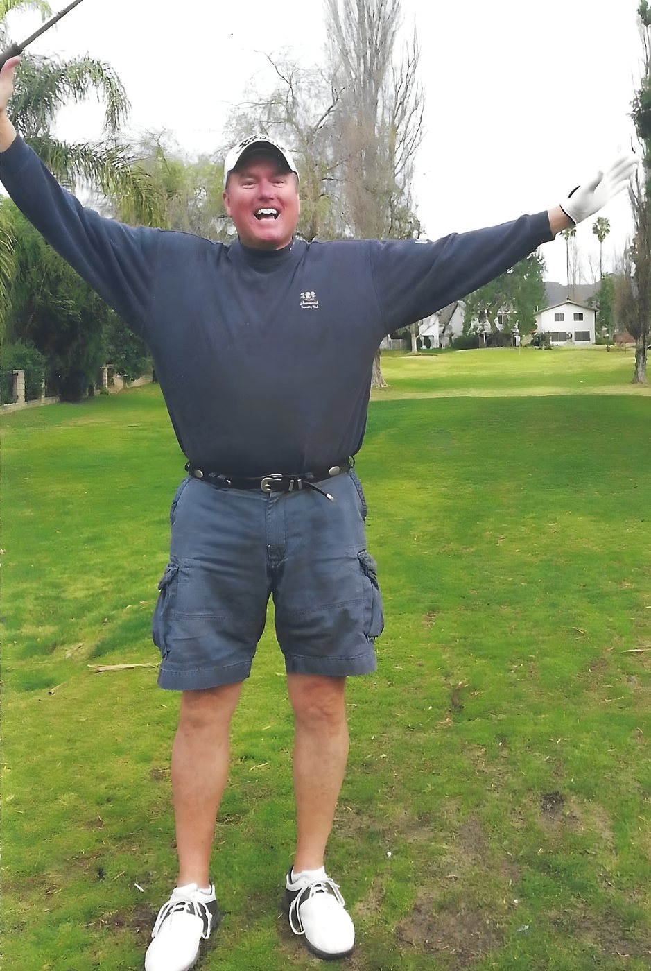 A golfer celebrating with arms raised on the fairway