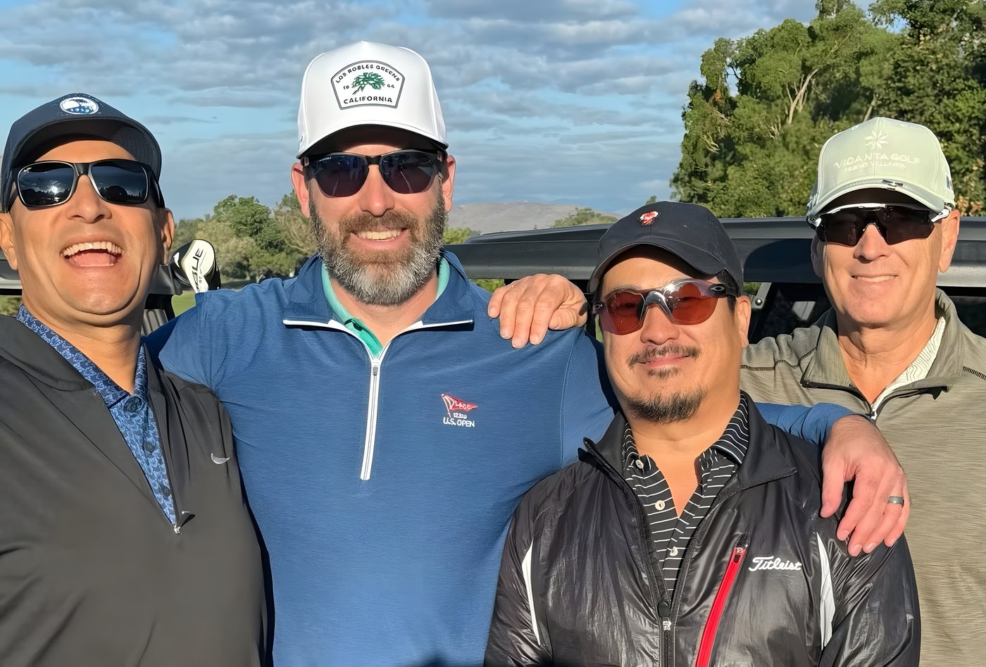 Four teammates with arms around each other on the course