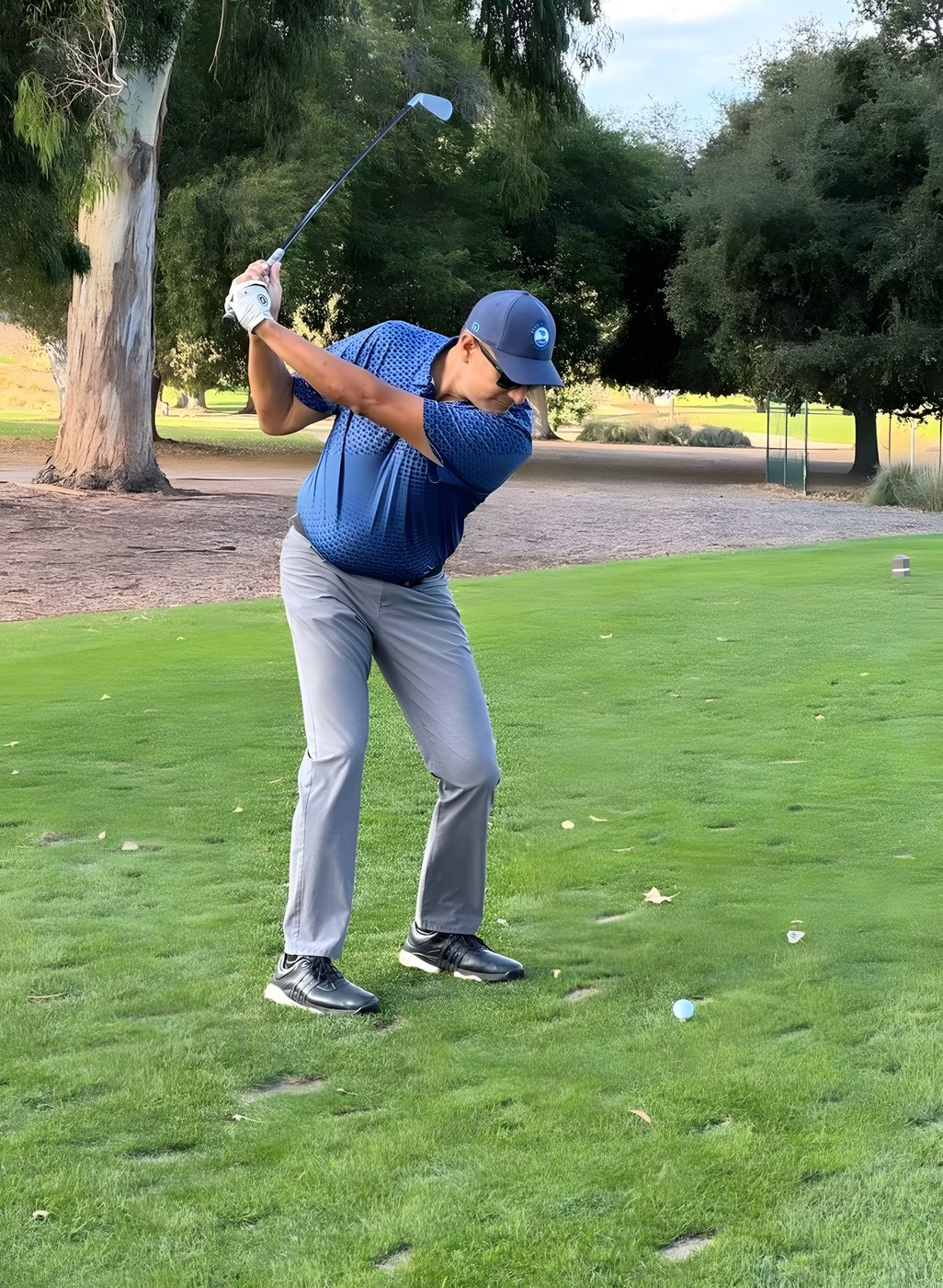 A golfer at the top of his backswing on the fairway