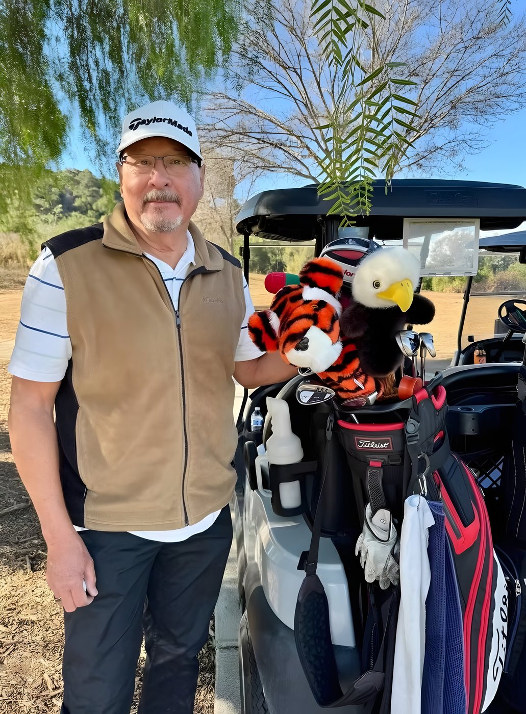 A player beside a cart loaded with golf bags