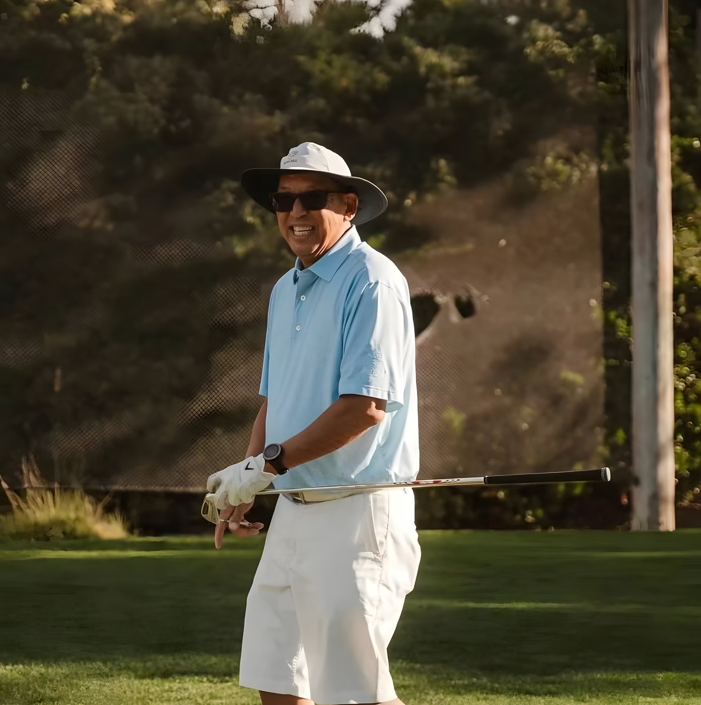 A golfer finishing his swing in the late afternoon light