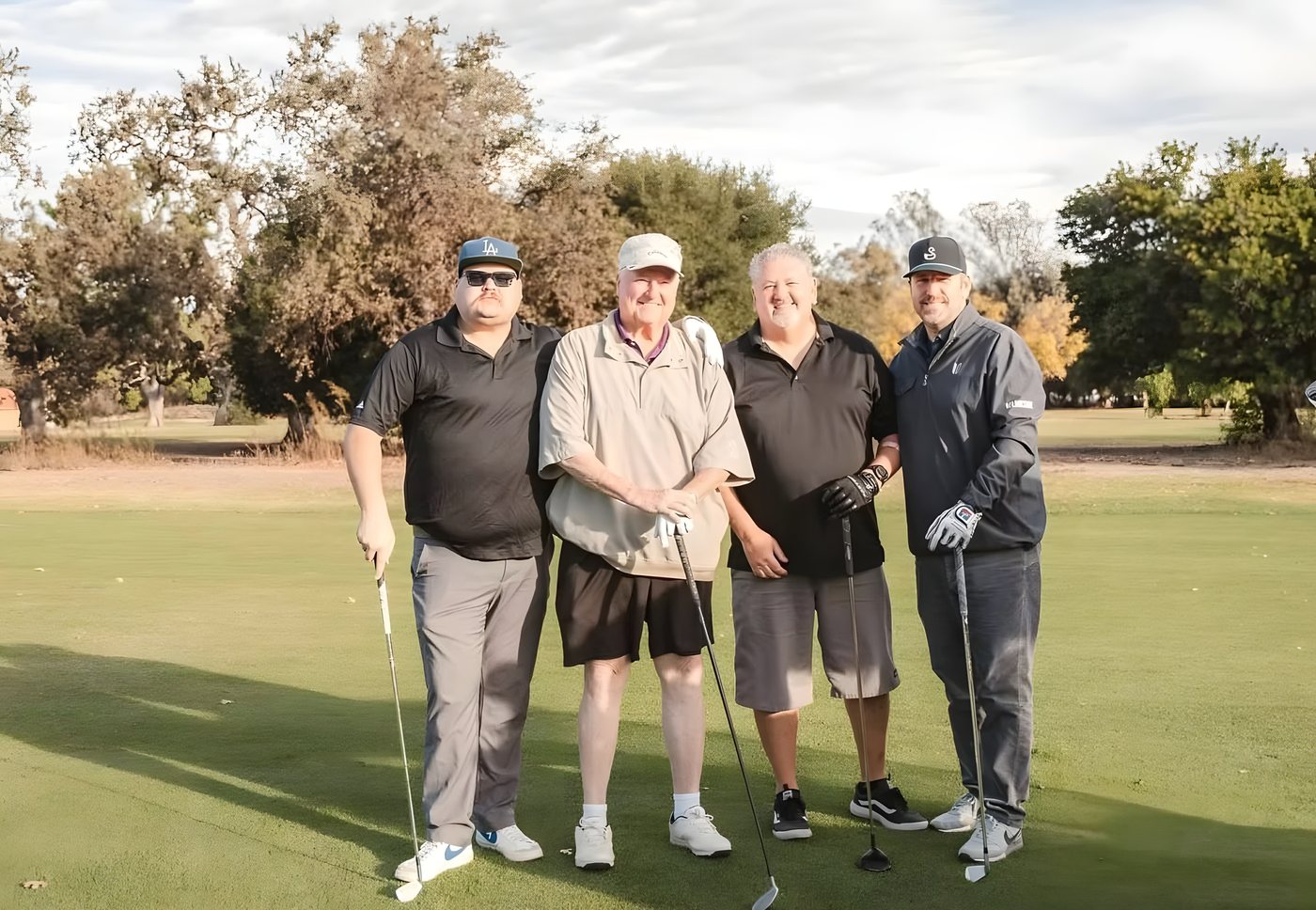 A foursome posing on the course in autumn light