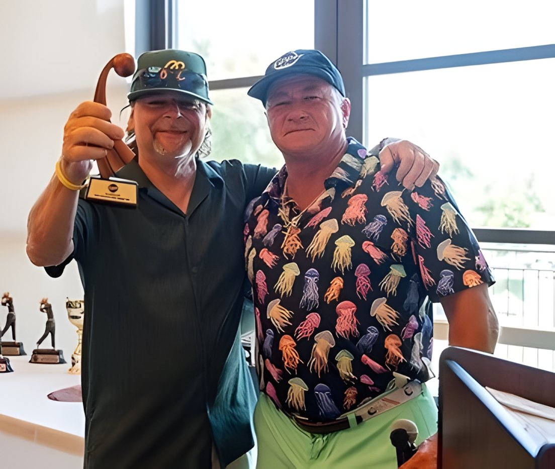 A contest winner holding his trophy with the tournament host